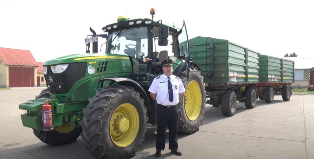Egy John Deere 8335 R típusú erőgép előtt álló rendőr mutatja be, amit minden traktorosnak tudnia kell - Fotó: Youtube